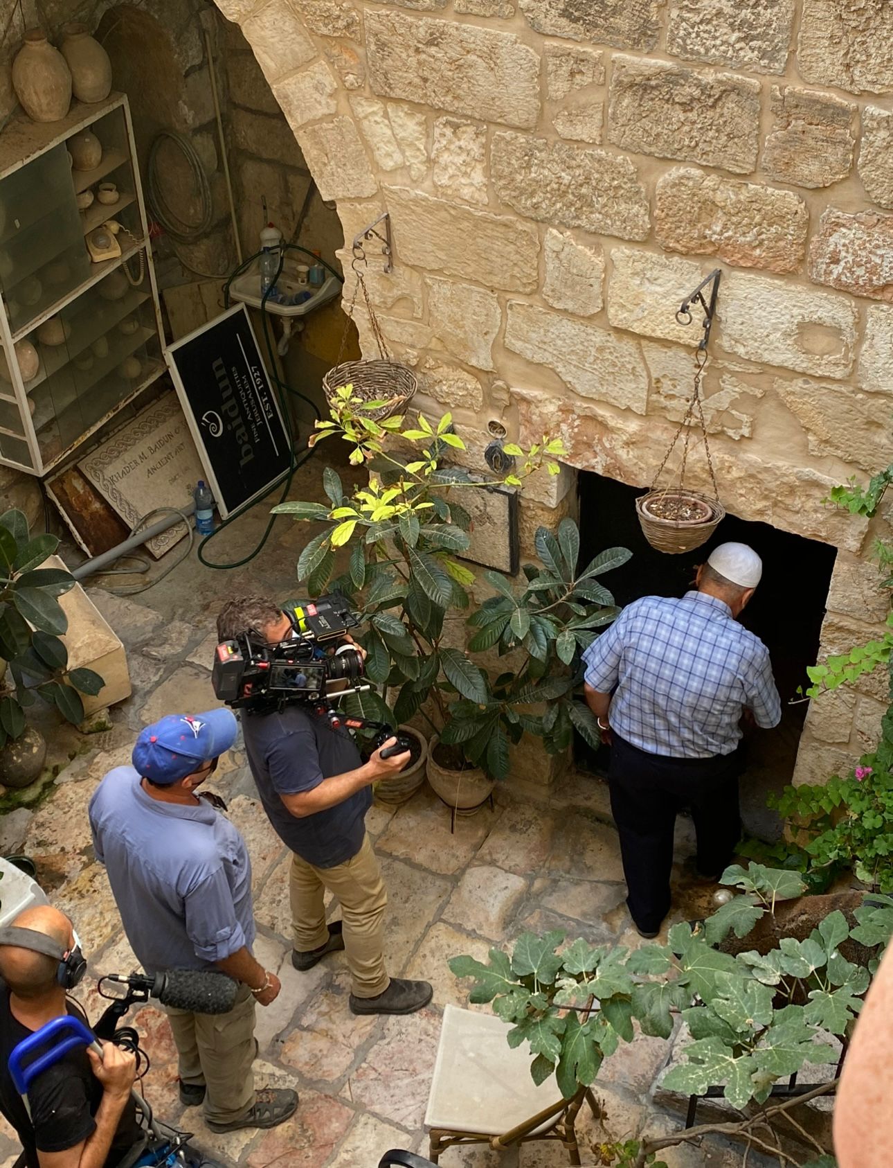 Cinematographer filming biblical expert interview in authentic Middle Eastern stone architecture setting 